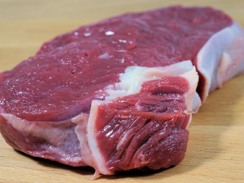 Corte de carne de res fresco sobre tabla de madera