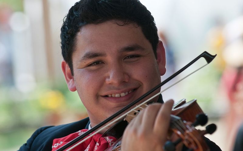 Joven músico de mariachi tocando el violín en una celebración